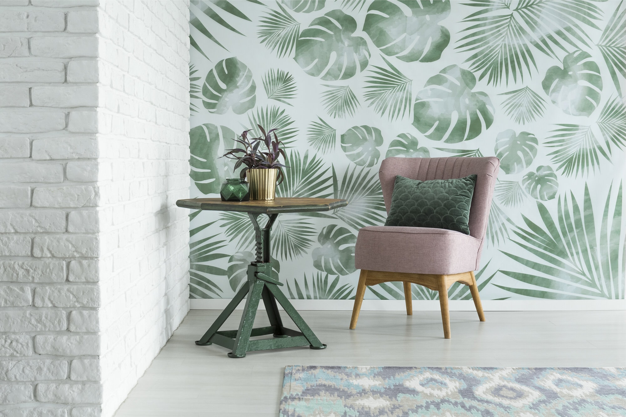 Green pillow on pink chair next to a table with plant in gold pot in room with floral wallpaper and brick wall by Frederick Painting in Frederick, MD