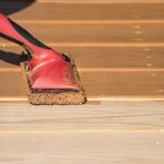 Staining a wooden deck with a staining pad.