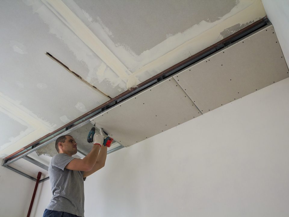 Construction worker assemble a suspended ceiling with drywall